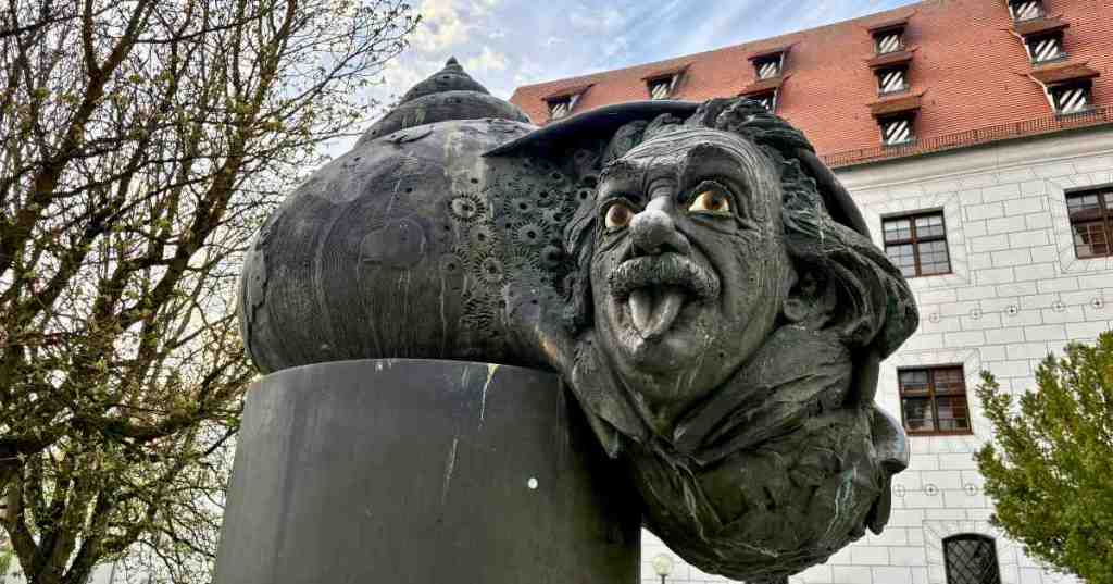 A bronze sculpture of Albert Einstein sticking his tongue out, emerging from a snail shell as part of the Einstein Fountain in Ulm, Germany.